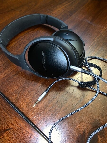 A pair of headphones with one end of an audio cable plugged in, lying on a table