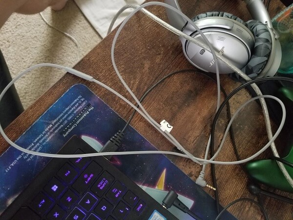 A pair of headphones plugged into a laptop on a messy desk