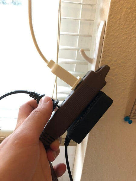 Somebody holding an electrical splitter with a cable plugged in it