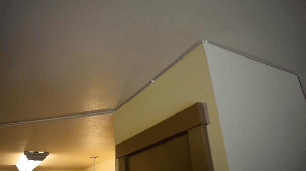 A room that has cable concealers going up a wall and a long the ceiling 