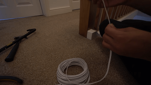 Somebody holding a coiled cable above a carpet with tools around it