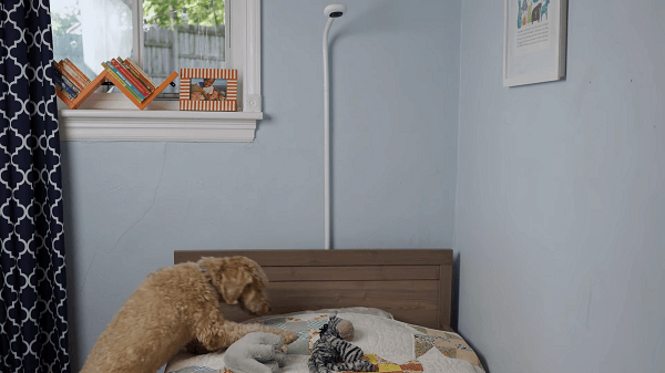 A baby camera above a crib with the cable hidden by a cord cover