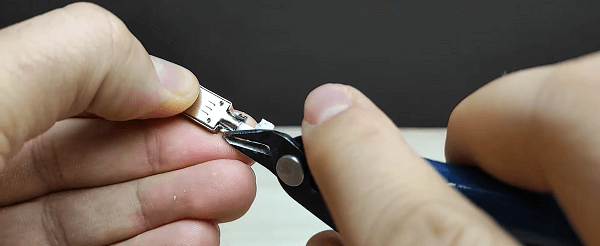 Somebody using pliers to open up the part holding the cable