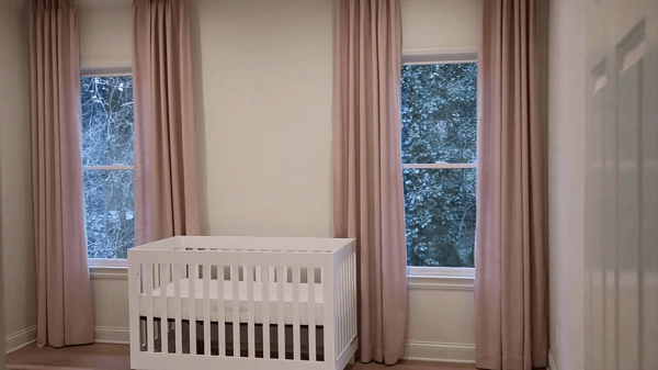 A room with a crib and curtains on both sides of it