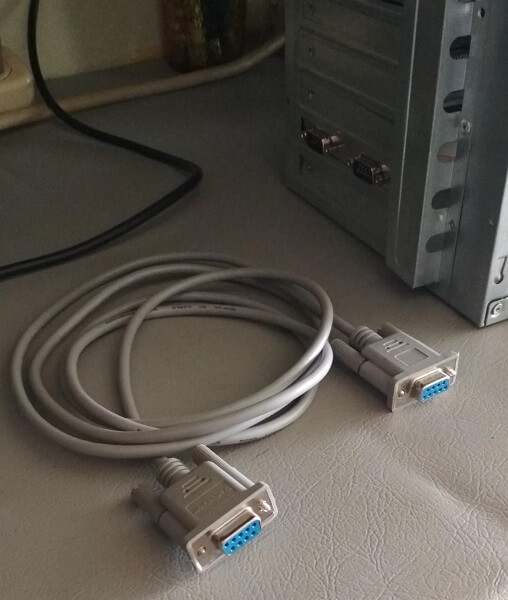 A grey VGA cable coiled next to an old PC