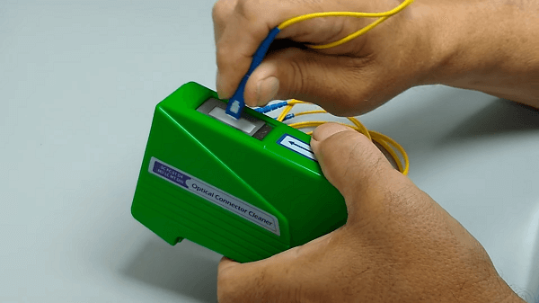 Somebody using a CLETOP-S to clean a fiber optic cable